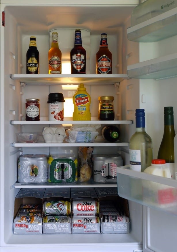 A fully stocked fridge containing cans, bottles, jars, eggs, milk, and other foods.