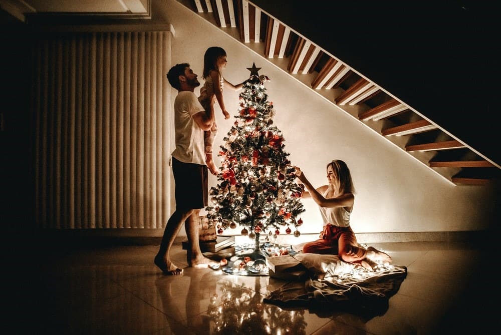 A family decorating a Christmas tree after cleaning their house.