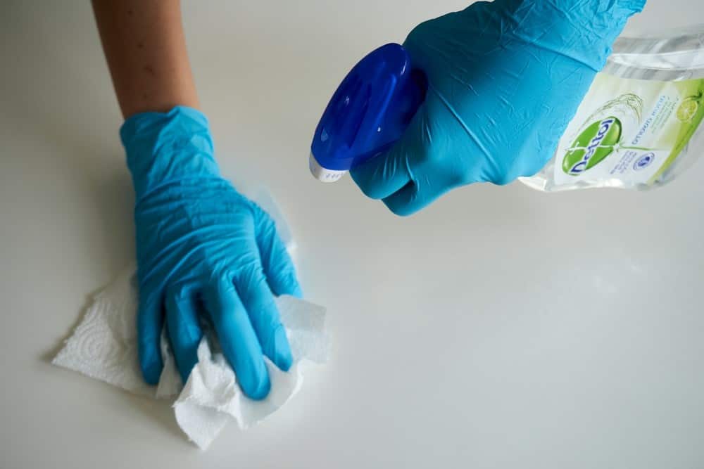 A cleaning specialist wearing gloves and disinfecting a table.