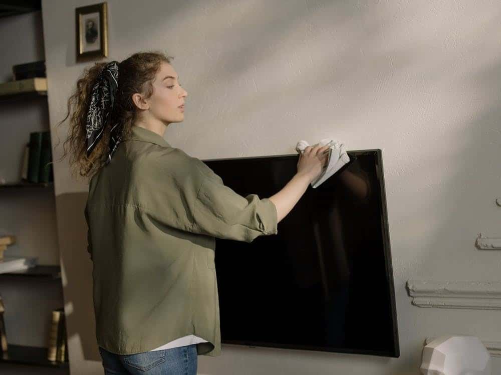 A woman cleaning her television